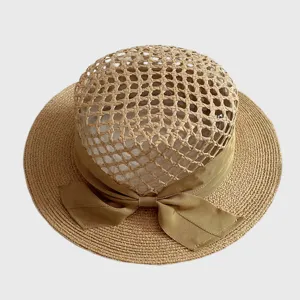 Hollow woven straw hat detail, classic raffia texture, flat top style with khaki ribbon bow.