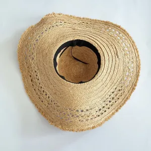 Detailed view of the wide brim raffia sun hat with frayed raw edge and black inner band design.