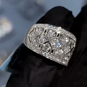 Close-up van brede geometrische geplaveide zirkonring met sprankelende details.