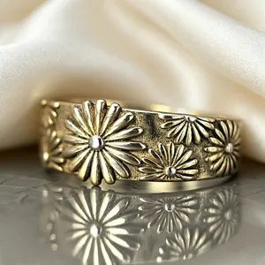 Eleganter breiter Ring mit erhabenen Gänseblümchen Motiven und poliertem Metall Finish.