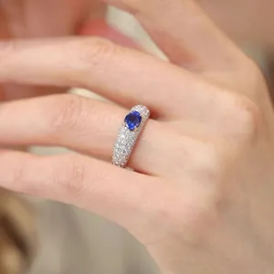 Detail view of wide pave-set diamond ring featuring a stunning oval blue sapphire centerpiece.