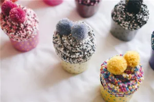 Nahaufnahme von gemütlichen flauschigen Kuchen-Socken in gepunkteten Bechern mit Bommeln.