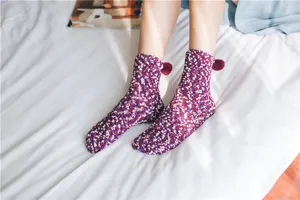 Close-up detail of cozy coral fleece fuzzy winter socks with cute pom-pom, soft floor wear.
