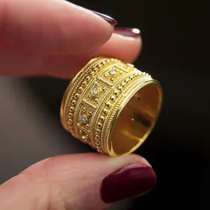 Anillo de oro ancho estilo palacio vintage con detalles de granulación y piedras brillantes.