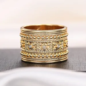 Primer plano detallado de un anillo de oro vintage ancho con abalorios y cordones.