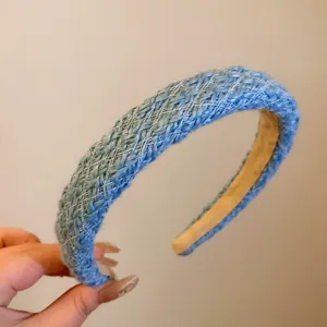 Détail du serre-tête tricoté bleu montrant la texture tressée et le design en peluche.