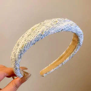 Gros plan du joli serre-tête large en tricot bleu avec de fins fils dorés, accessoire élégant.