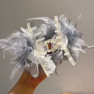 Close-up detail of elegant feather hair claw clip, fluffy tulle design, sturdy plastic teeth.