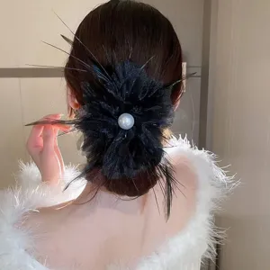 Detailed view of the elegant black feather hair claw with a central white pearl ornament.