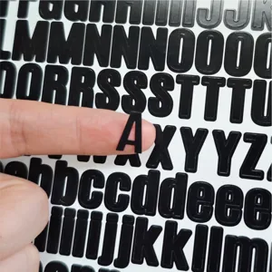 Close-up detail shot of black adhesive alphabet letter stickers showing size and texture clearly.