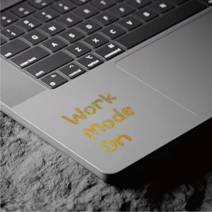 Vue détaillée d'autocollant de lettre pailleté doré sur surface d'ordinateur, parfait pour le DIY.