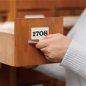 Vue rapprochée d'un autocollant numéroté en vinyle sur un tiroir en bois de bureau.