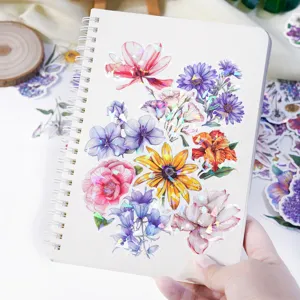 Dettaglio adesivi floreali olografici impermeabili che mostrano design colorati su un taccuino.