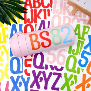 Botella termo rosa con estampado de letras sobre pegatinas de alfabeto coloridas.