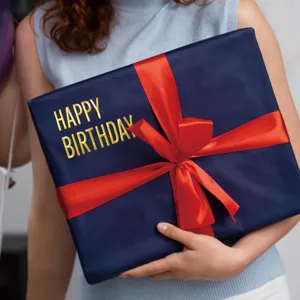 Detail shot of 3D metallic gold letter stickers spelling happy birthday on a gift box.