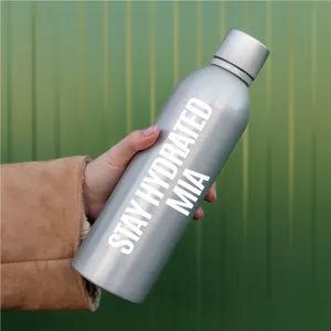 Primer plano detallado de una botella de agua plateada con pegatinas de vinilo blanco.
