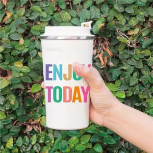 Vista detallada de la taza de viaje blanca con diseño de tipografía motivacional.