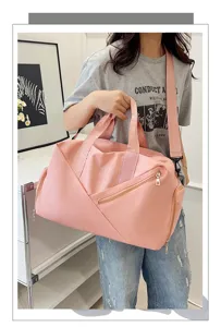Vue détaillée d'un grand sac de voyage rose avec une bandoulière et une poche zippée.