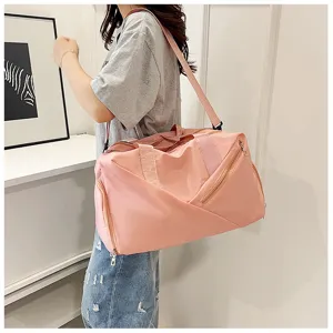 Détail de sac de voyage rose avec grande capacité, bandoulière et poche zippée latérale pratique.