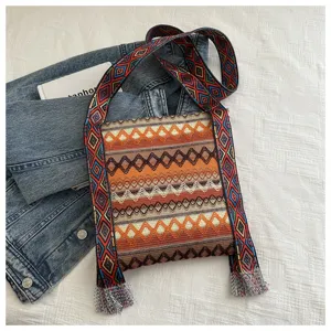 Sac à bandoulière tissé style ethnique pour femme avec large sangle et pompons.