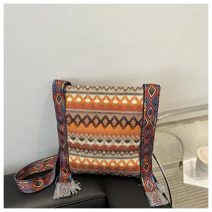Sac bandoulière tissé style ethnique pour femme avec une large sangle et des franges.
