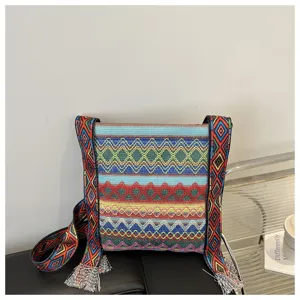 Sac bandoulière tissé ethnique rétro pour femmes avec motif géométrique coloré et pompons.