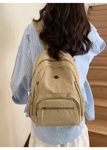 Vue détaillée d'un sac à dos décontracté beige avec poches zippées pour le voyage quotidien.
