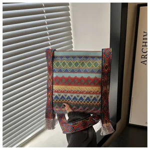 Détail de sac bandoulière tissé style ethnique avec motif géométrique coloré et frange.