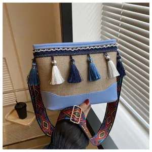 Vue détaillée du sac à bandoulière ethnique avec pompon et sangle tissée colorée.