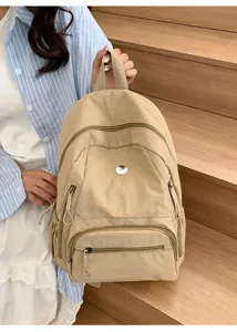 Vue détaillée du sac à dos de voyage beige décontracté avec poches zippées multiples.