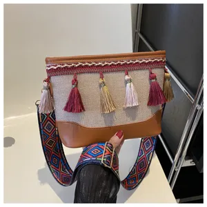 Détail de sac à bandoulière ethnique avec lanière géométrique colorée et glands décoratifs.