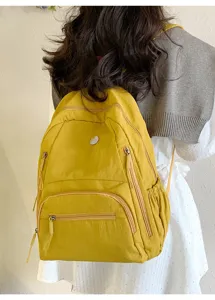 Détail du sac à dos jaune décontracté avec plusieurs poches pratiques et bretelles confortables.