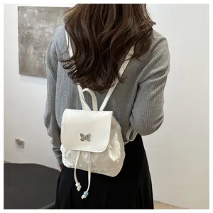 Vue détaillée du petit sac à dos blanc pour femme avec charm papillon et cordon de serrage.