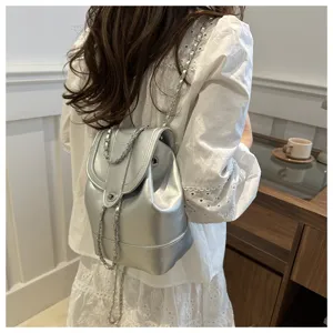 Vue détaillée du sac à dos argenté métallisé élégant avec bretelles chaînes et fermoir chic.