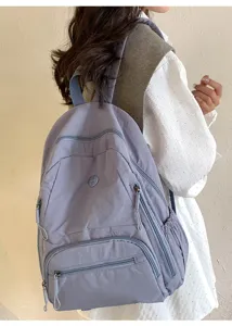 Sac à dos de transport léger avec plusieurs poches zippées et un design gris-bleu élégant.