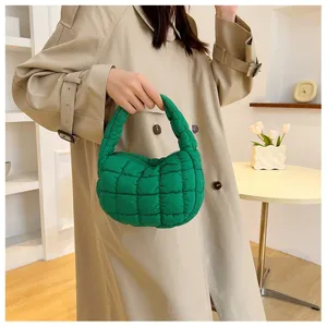Gros plan sur les détails du sac à main matelassé vert, texture douce et fermeture éclair.