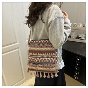 Gros plan sur le sac bandoulière tissé bohème avec des motifs ethniques et des pompons.