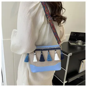 Vue détaillée du sac bandoulière bohème avec sangle tissée colorée, pompons et cuir bleu.