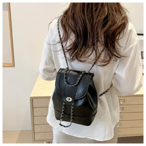 Petit sac à dos noir pour femme en cuir avec bandoulières chaînes et fermoir tournant chic.