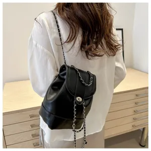 Vue détaillée du mini sac à dos noir en cuir avec des bretelles à chaîne et fermoir chic.