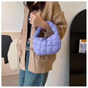 Gros plan d'un sac à main matelassé violet élégant porté par un mannequin dans une tenue.