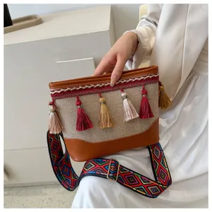 Gros-plan du sac bandoulière en toile ethnique, avec glands colorés et sangle à motifs.