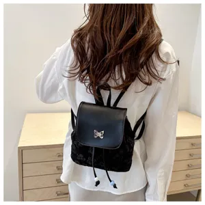 Vue de détail du petit sac à dos seau noir avec ornement de papillon en métal et cordon.