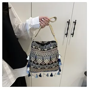 Gros plan sur les détails du sac bandoulière ethnique avec pompons et imprimé géométrique rétro.