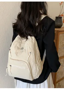 Détail de sac à dos beige montrant des poches multiples et lanières résistantes.