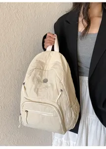 Vue détaillée du sac à dos beige avec fermetures à glissière pour le quotidien.