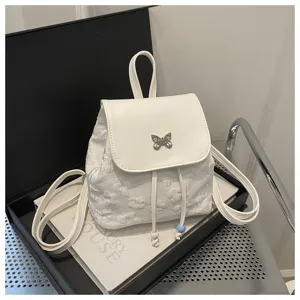 Joli mini sac à dos blanc brodé de fleurs avec un ornement de papillon en métal chic.