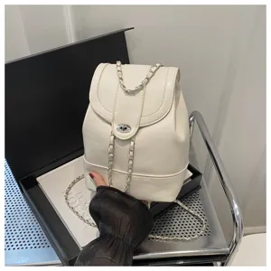 Gros plan du sac à dos blanc mode avec fermeture rotative en métal et lanières élégantes.