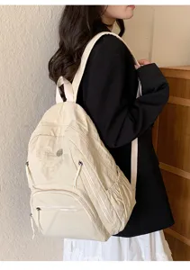 Vue détaillée du sac à dos beige décontracté avec plusieurs poches zippées pour le quotidien.