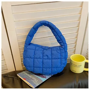 Gros plan sur un sac à main matelassé bleu vif montrant une texture douce et des coutures.